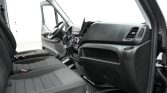 Interior of a van cab with two front seats, steering wheel, and dashboard controls.