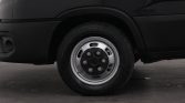 Close-up of a black van's front wheel with a silver steel rim and lug nuts visible
