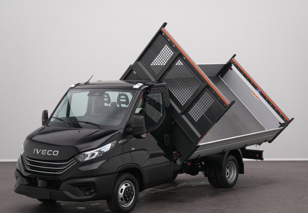 Black Iveco dump truck with raised tipping bed, showing cargo bed tilted upward for unloading in a neutral studio setting.