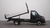Black cab truck with a raised tilting flatbed supported by hydraulic struts to dump material.