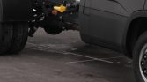 Tow hitch and yellow safety latch attached to the back of a dark van or box truck.