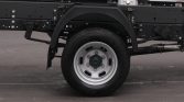 Rear section of a commercial truck chassis with a single wheel, black frame, and exhaust pipe visible beneath the bed.