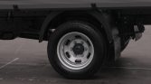 Rear truck wheel with silver rim and black tire under a cargo bed; shows wheel well and mudguard