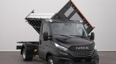Black Iveco dump truck with raised tilting bed, ready to unload in a studio setting, gray background
