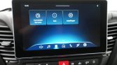 In-car infotainment screen showing three tiles: Connected Services, Klok (Clock), and Instellingen (Settings) on a blue gradient background, with car dashboard below.