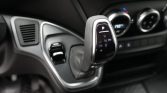 Close-up of a car's automatic gear selector with P R N D M and +/- on a textured knob, set in a modern dashboard interior.