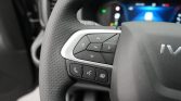 Close-up of a car steering wheel with multimedia controls (OK button, arrows) and phone/voice buttons on the left spoke