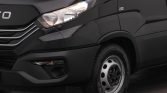 Front-left portion of a dark van showing the headlight, grille, bumper, and front wheel with silver rims