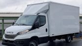 Front three-quarter view of a white Iveco box truck with a tall cargo box, parked on a wet surface.