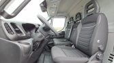 Interior of a van cabin showing the driver seat and two passenger seats in gray fabric