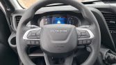 Steering wheel of an Iveco vehicle with built-in control buttons and a digital dashboard behind it.