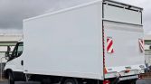 Rear view of a white box truck with closed cargo doors and red‑and‑white reflective safety markings on the back.