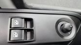 Car door panel showing two power window switches with window icons and a round side-mirror adjustment knob to the right