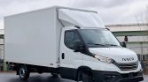 White Iveco box truck with a large cargo box, parked on a wet pavement under a cloudy sky.