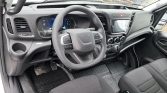 Interior of a vehicle cockpit showing a multifunction steering wheel, digital instrument cluster, and central touchscreen display with climate controls below.