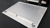 Aluminum truck loading ramp extended to ground, ready for cargo loading.