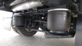Underbelly of a heavy truck showing air suspension airbags and drivetrain components, with a large rubber air spring and metal chassis above.