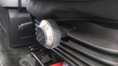 Round metal car-seat adjustment dial with a numbered scale (0–110) mounted on the side of the seat, used to adjust seat position/tilt.