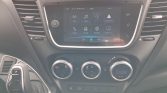 Car interior dashboard with a touchscreen infotainment system showing app icons and climate controls above the gear shifter on the left side of the console