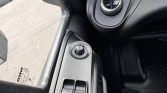 Close-up of a car's driver-side panel showing the round mirror-adjustment knob and two window switches beneath it.