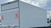 White box truck trailer with closed rear doors, red-and-white hazard panels, and SAXAS branding, parked on a road under cloudy sky