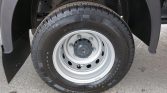 Wheel of a cargo van: steel rim with five lug nuts, mounted with a Continental tire; mudflap and wheel well visible in the background.