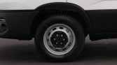 Close-up of a white van's wheel: tire on a silver steel rim with black hub, wheel arch visible in black body paneling.