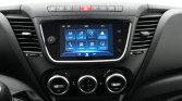 Center console of a car showing a touchscreen infotainment display with app icons (Radio, Media, Apple CarPlay, Android Auto) and climate control knobs below.