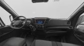 Driver's cabin of a van with left-hand steering wheel, central touchscreen, climate controls, and gear lever visible between the seats.