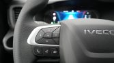 Close-up of a car steering wheel with left-side control cluster including OK, arrows, and phone/voice buttons.