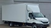 White box truck parked beside a gray industrial building.