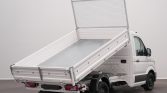 White utility pickup with a tilted flatbed and metal mesh tailgate, ready to load or unload.