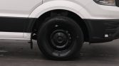 Close-up of the front wheel and right side of a white van, highlighting the black bumper and tire/rim.