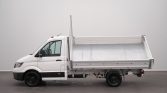 White cab-forward flatbed truck with an empty metal cargo bed, side view in a neutral studio setting.