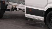 Side view of a white commercial truck with an exposed flatbed chassis and a visible rear wheel on the right side.