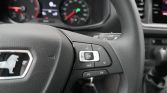 Steering wheel with integrated controls (OK button) and dash gauges blurred in the background, car interior detail.