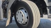 Front wheel of a heavy-duty truck with a Bridgestone tire, white steel hub, and a mudguard on the left side.