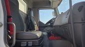 Interior view of a truck cab showing the driver's seat, steering wheel, and dashboard with a red coiled cord on the floor by the passenger area