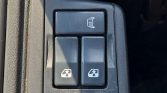 Car interior control panel on a door armrest with a top button showing seat heater icon and two lower window/lock controls
