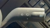 Close-up of a car’s windshield wiper control stalk on the steering column, showing front-wiper icons and a + speed control.