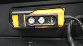 Yellow handheld winch controller mounted in a vehicle, with two arrow buttons and an SPX logo.