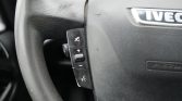 Steering wheel of a vehicle with left-side audio controls (volume up/down, mute) and a voice/phone button, IVECO emblem on the airbag cover