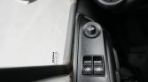 Close-up of a car's driver-side door panel with two power window switches and a circular mirror-adjustment knob
