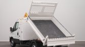 White dump truck with its hydraulic bed raised for unloading, parked on a blank floor.