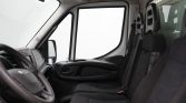 Interior of a van cab with a steering wheel, dashboard, and two front seats viewed from the passenger side.