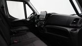 Front cabin of a van showing the steering wheel, center touchscreen, and two black cloth seats in the dashboard area .