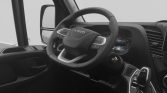 Steering wheel and dashboard of an Iveco vehicle, with a digital instrument cluster and gear shifter visible nearby in a modern cabin.