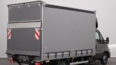 Grey delivery truck with a tall covered cargo box viewed from the rear-right, parked indoors.