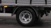 Close-up of a gray commercial truck wheel with silver rim, black tire, and a grey cargo bed above the wheel