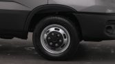Close-up of a van's front wheel showing the silver hubcap and black tire against a dark lower body panel.